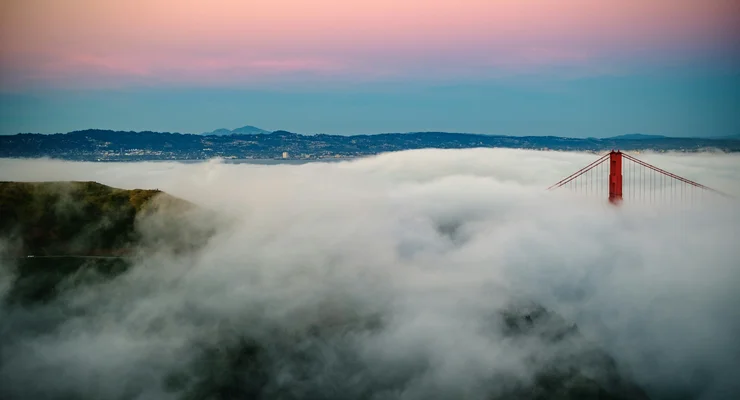 Golden Gate Bridge tower emerging above fog at dawn - representing visibility and the risk of being obscured in a crowded information landscape